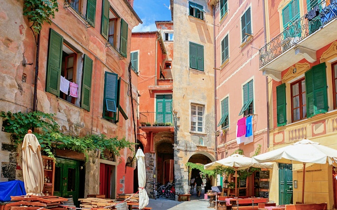 Colorful buildings and outdoor cafes in a narrow street of Cinque Terre, Italy.