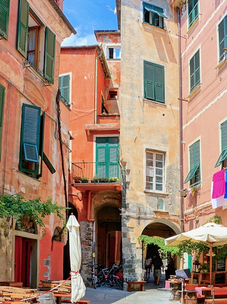 Colorful buildings and outdoor cafes in a narrow street of Cinque Terre, Italy.