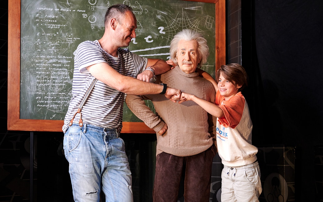 Visitors posing with Albert Einstein wax figure at Madame Tussauds Berlin.