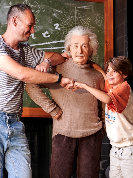 Visitors posing with Albert Einstein wax figure at Madame Tussauds Berlin.