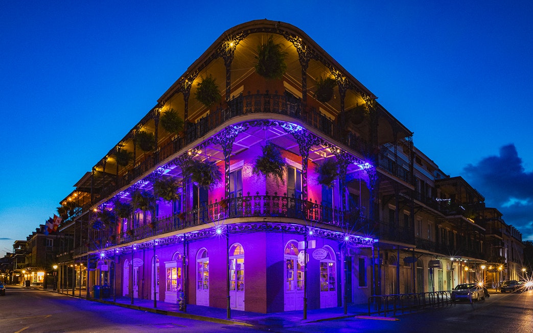 Bourbon Street balconies illuminated at night in New Orleans.