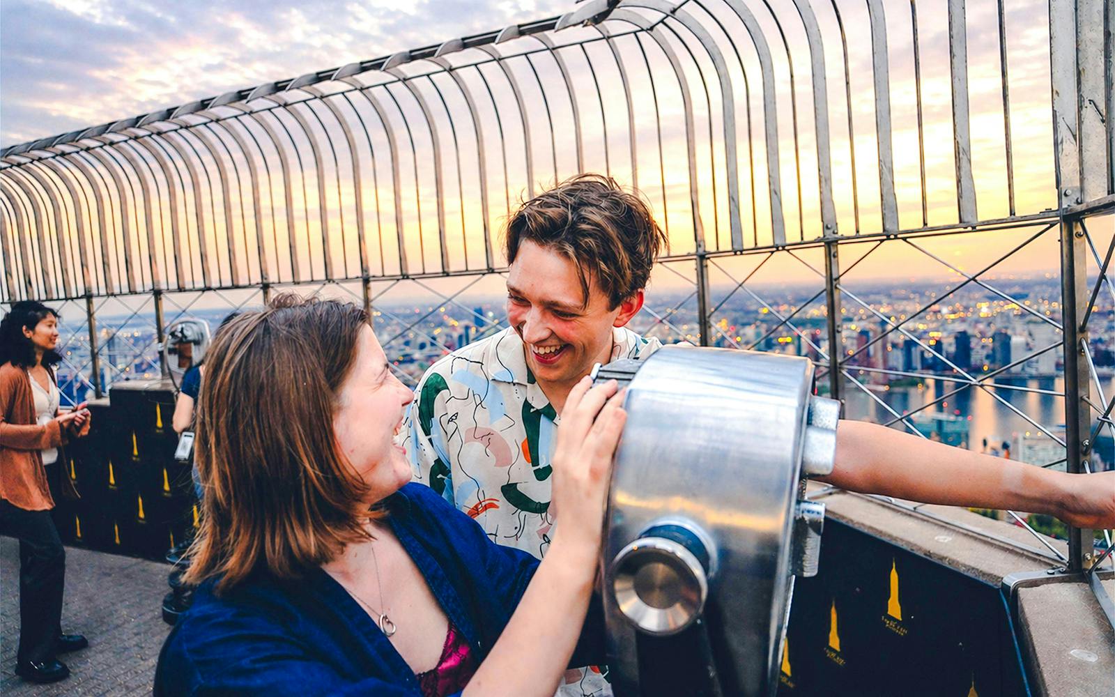 Couple enjoying sunset view from Empire State Building observation deck.