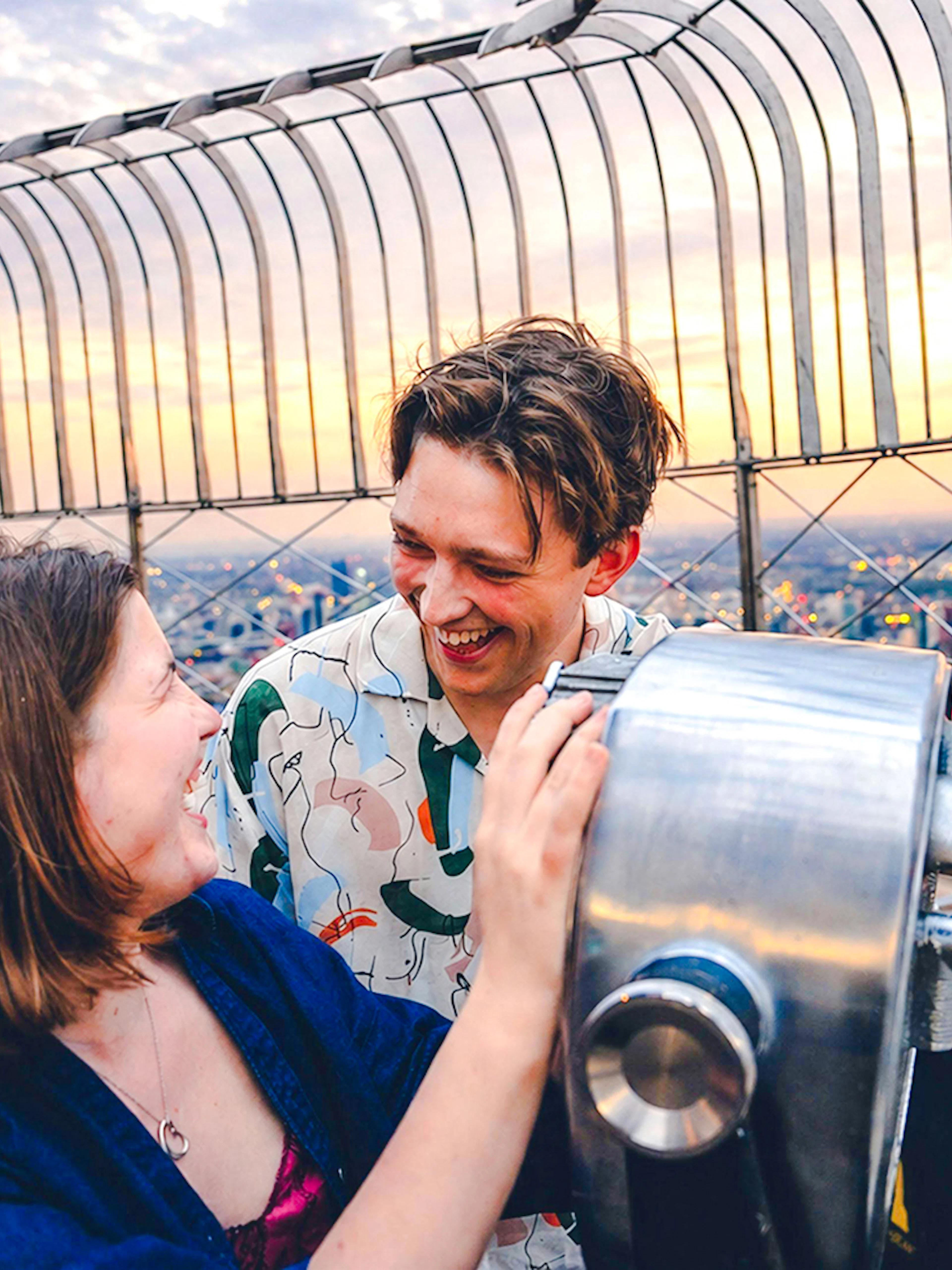 Couple enjoying sunset view from Empire State Building observation deck.