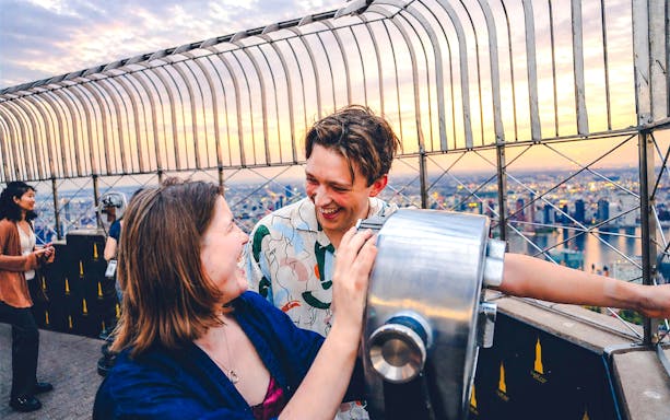 Couple enjoying sunset view from Empire State Building observation deck.