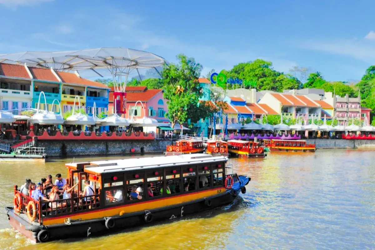 Boat cruising along Singapore River with colorful buildings at Clarke Quay in the background.