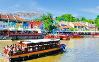 Boat cruising along Singapore River with colorful buildings at Clarke Quay in the background.