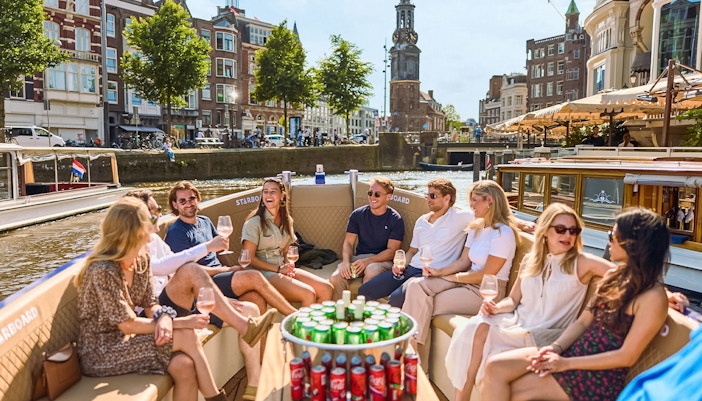Amsterdam canal cruise boat on water with passengers enjoying Red Light District views.