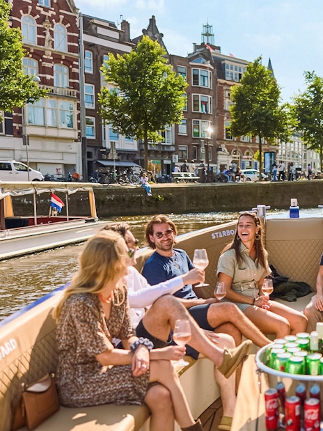 Group enjoying drinks on a canal cruise in Amsterdam's Red Light District.