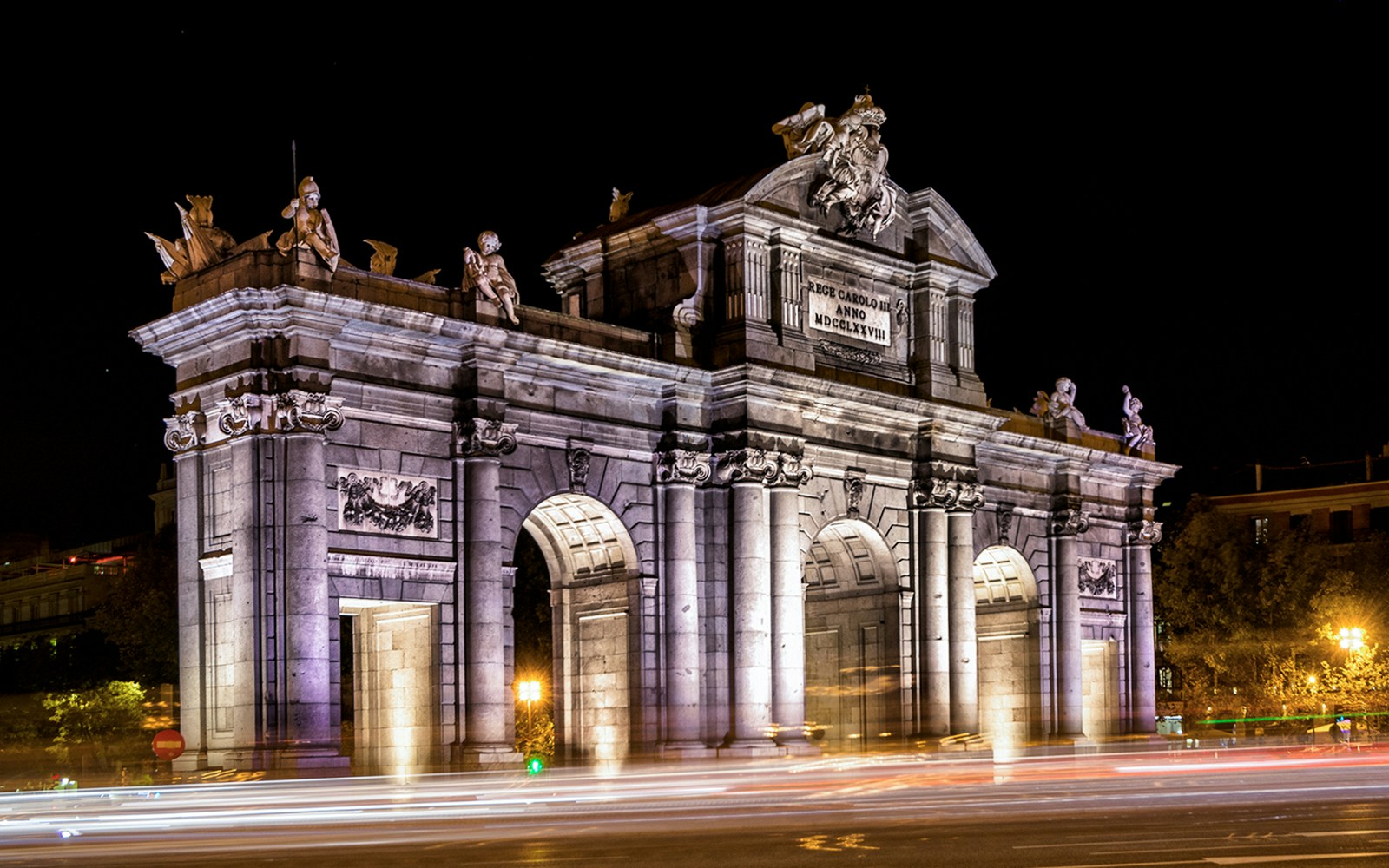 Puerta de Alcalá illuminated at night in Madrid, Spain.