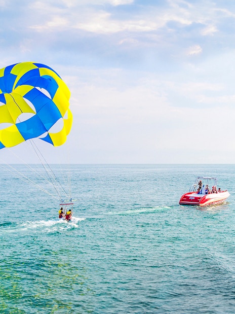 Parasailing over the ocean in Dubai with a colorful parachute and speedboat.