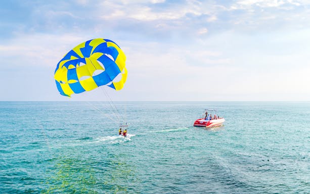 Parasailing over the ocean in Dubai with a colorful parachute and speedboat.