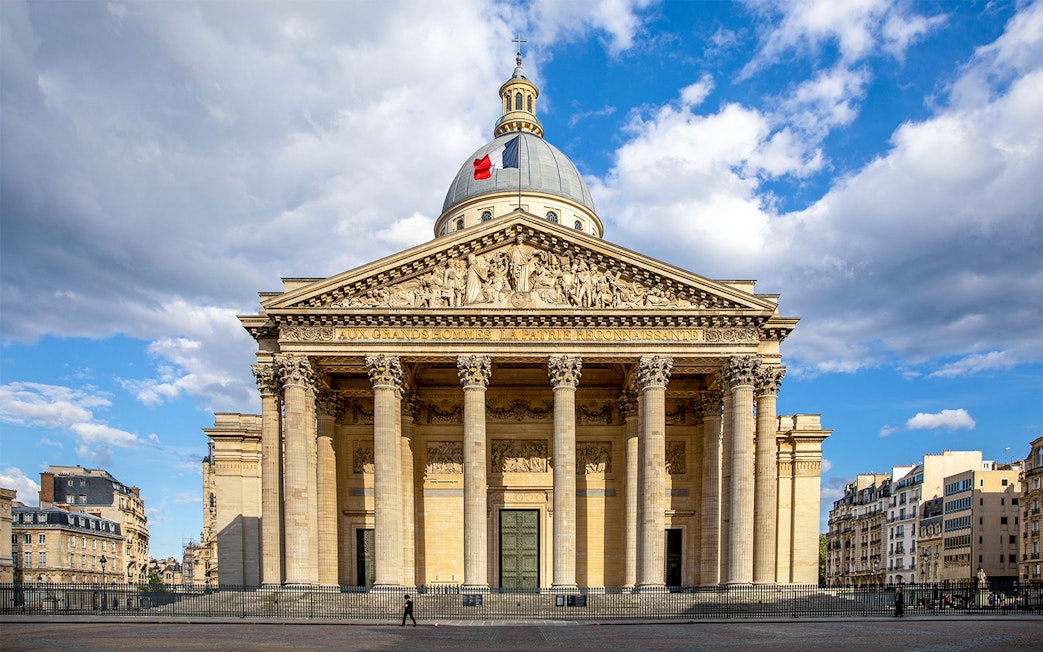 Pantheon in Paris with neoclassical facade and French flag on dome.