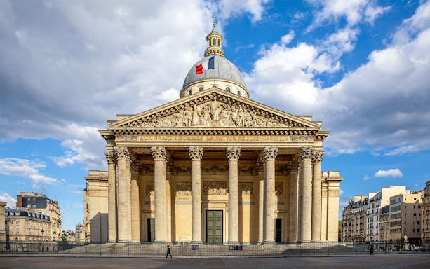 Pantheon in Paris with neoclassical facade and French flag on dome.