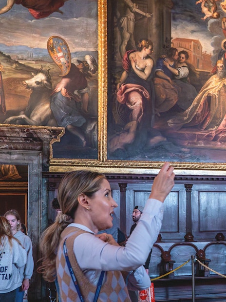 Tour group observing artwork and clock inside Doge's Palace, Venice.