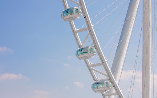 Pods of Ain Dubai Ferris wheel against a clear blue sky.