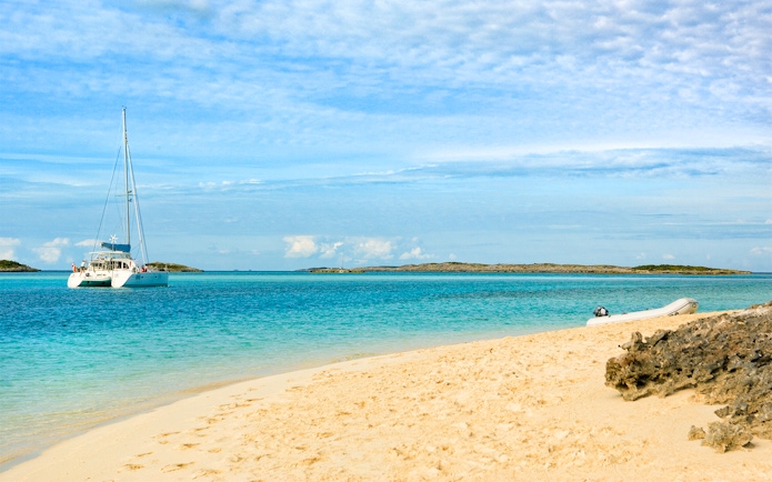 Sailboat anchored near sandy beach at Allen Cay, Exumas, Bahamas.