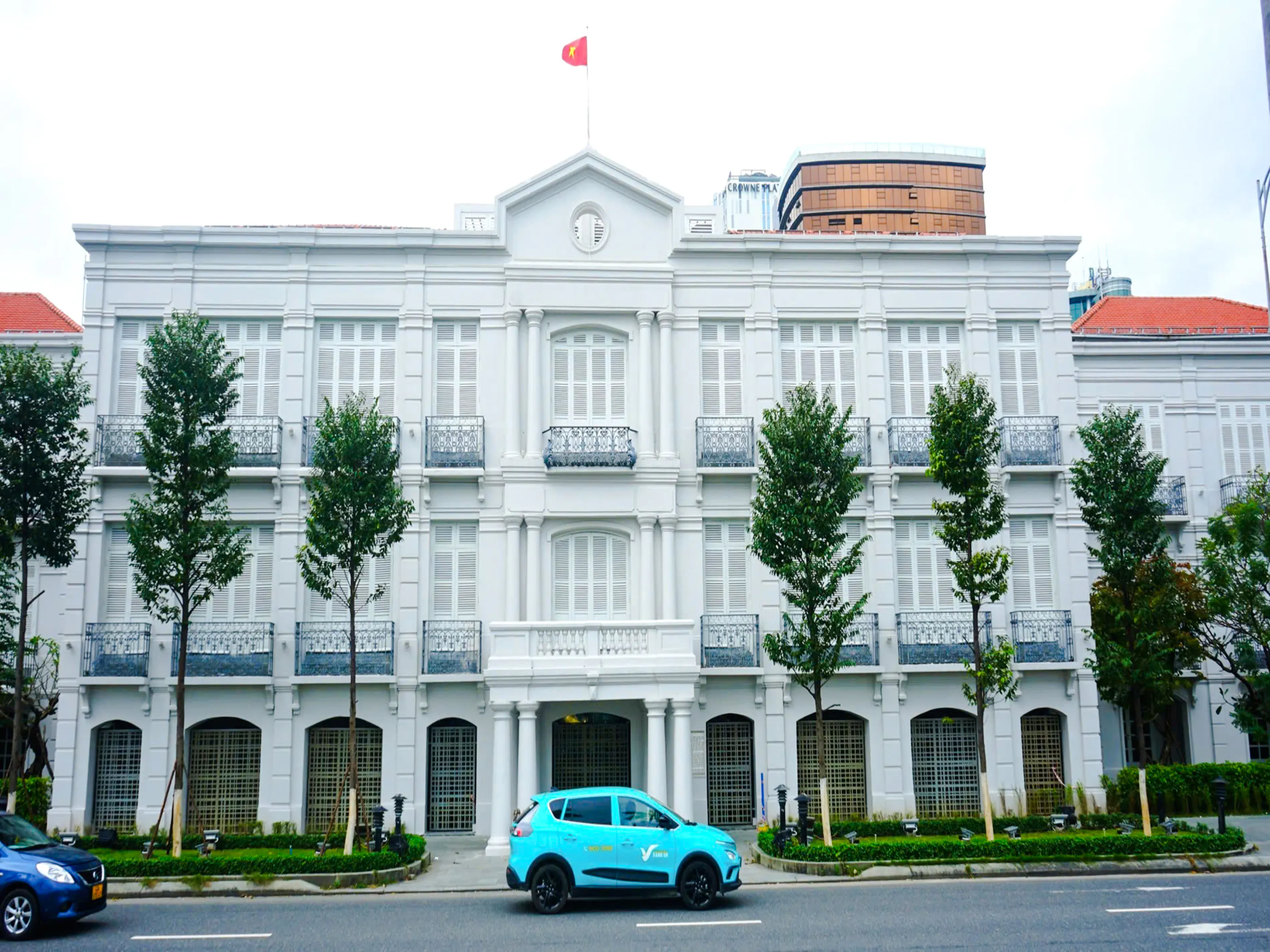 Historic colonial building in Da Nang with a blue car parked in front.
