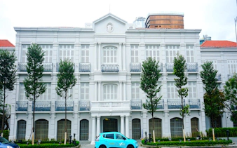 Historic colonial building in Da Nang with a blue car parked in front.
