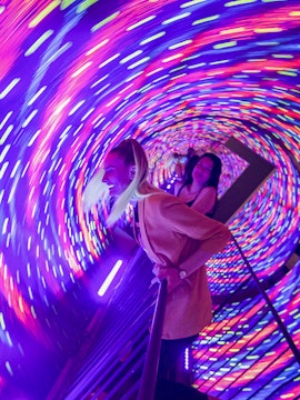 Visitors enjoying the colorful vortex tunnel at Museum of Illusions Seville.