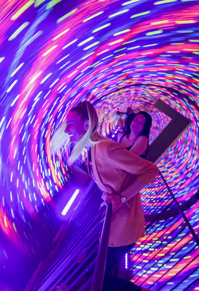 Visitors enjoying the colorful vortex tunnel at Museum of Illusions Seville.