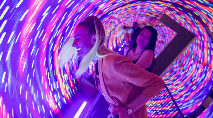 Visitors enjoying the colorful vortex tunnel at Museum of Illusions Seville.