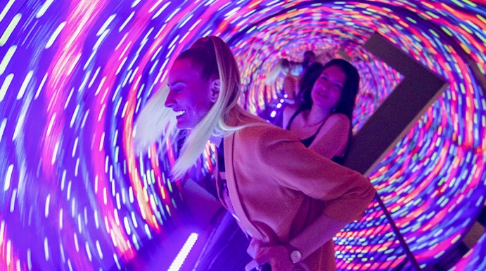 Visitors enjoying the colorful vortex tunnel at Museum of Illusions Seville.