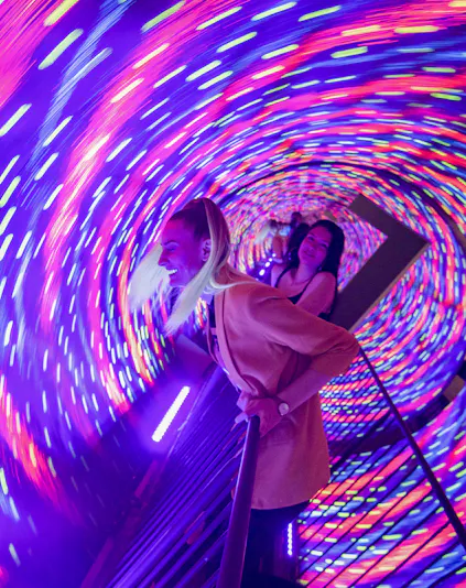Visitors enjoying the colorful vortex tunnel at Museum of Illusions Seville.
