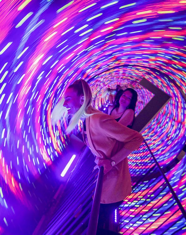 Visitors enjoying the colorful vortex tunnel at Museum of Illusions Seville.