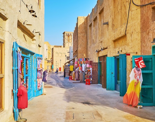 Market street in Al Fahidi Historical District, Dubai, with colorful textiles and traditional architecture.