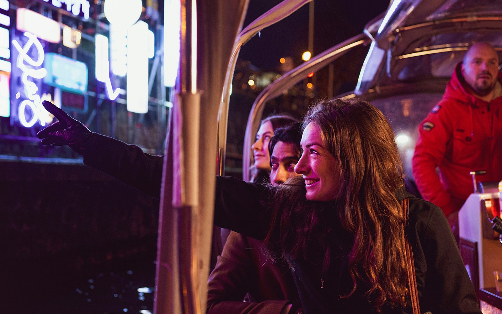 Guests on a boat tour enjoying Amsterdam Light Festival installations at night.