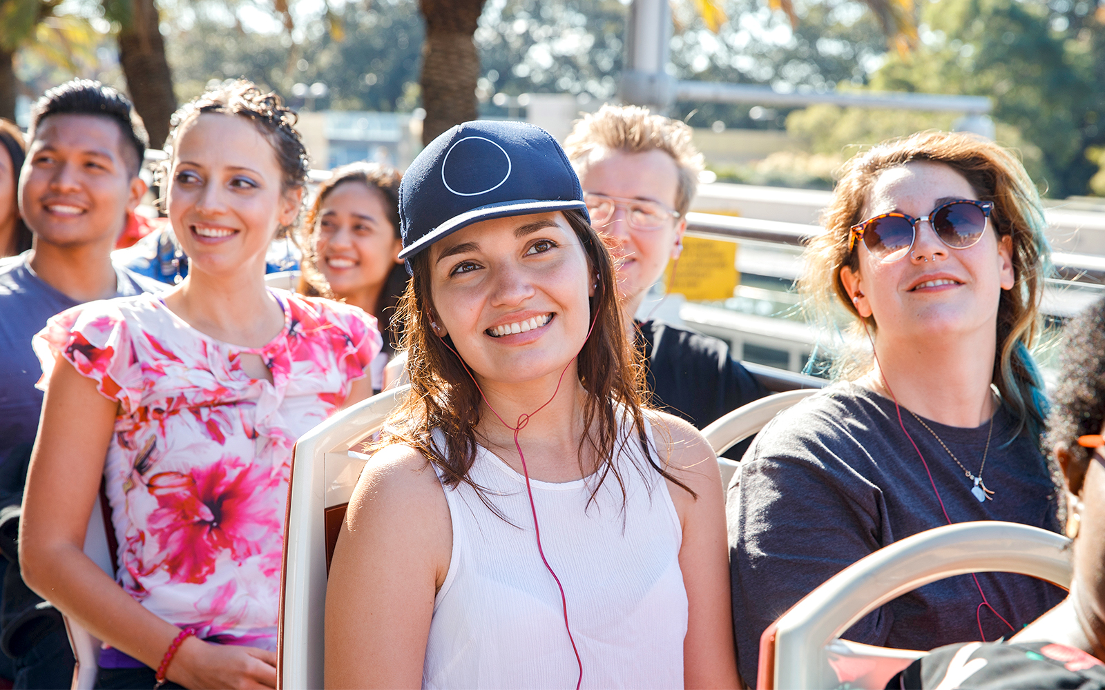 Girl enjoying audio guide on open-top bus tour.