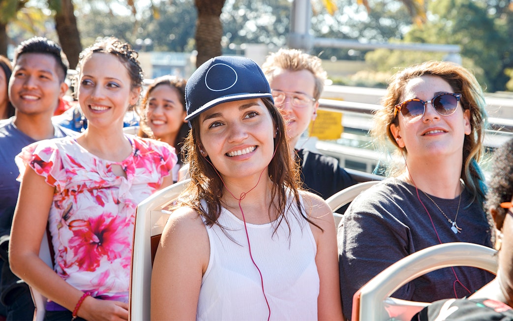 Girl enjoying audio guide on open-top bus tour.