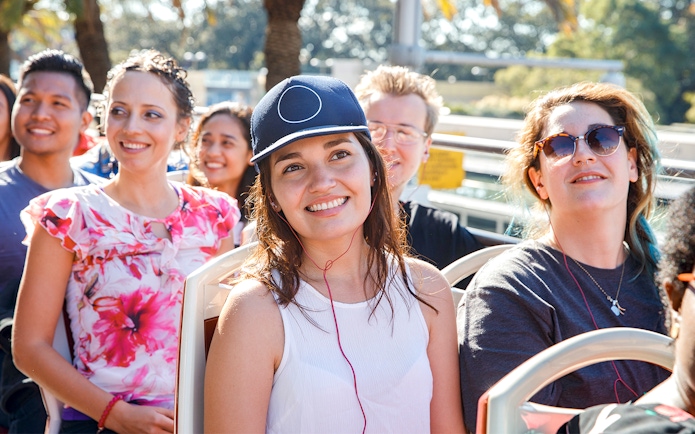 Girl enjoying audio guide on open-top bus tour.