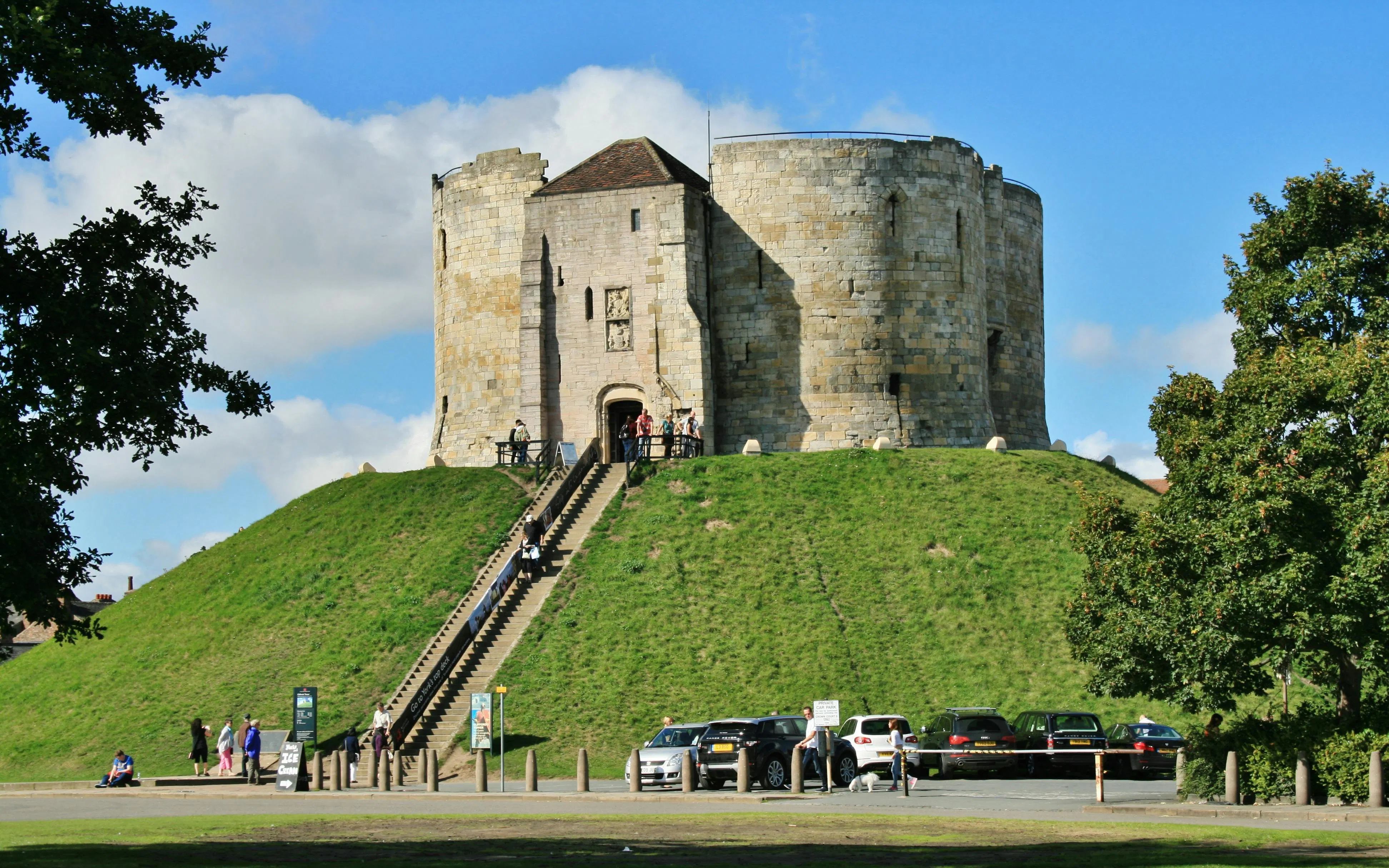 Clifford's Tower in York, England, with visitors ascending the steps.