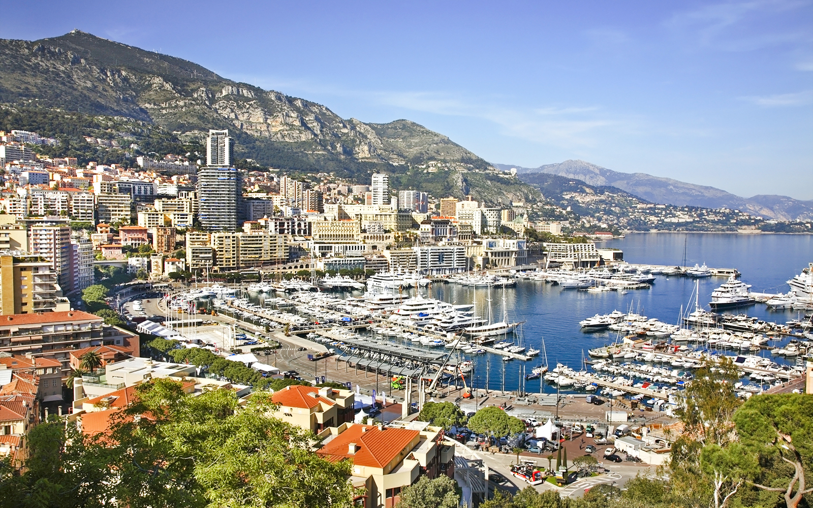 Monte Carlo harbor with yachts and cityscape against mountain backdrop.