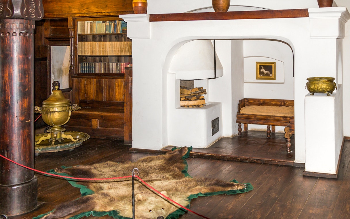 Bran Castle library interior with bookshelves, fireplace, and bear rug.