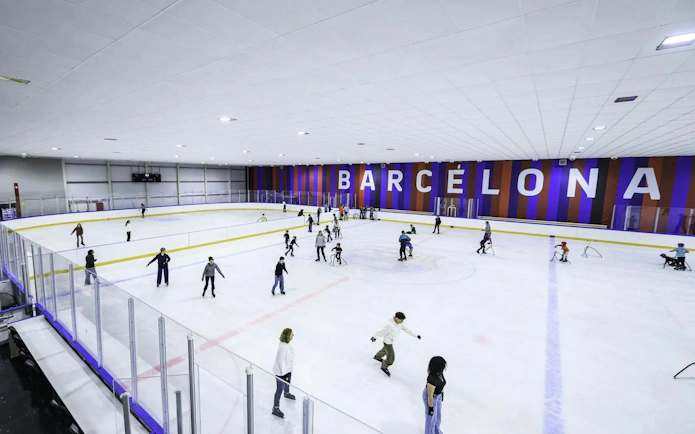 People ice skating at FC Barcelona Ice Rink with large "Barcelona" sign in the background.