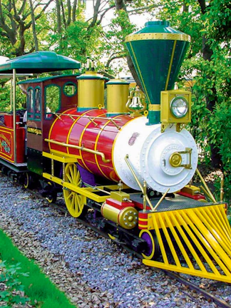 Colorful train ride at Hirakata Park, Japan, surrounded by lush greenery.