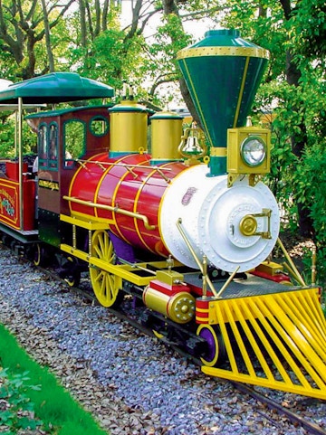 Colorful train ride at Hirakata Park, Japan, surrounded by lush greenery.