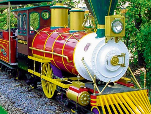 Colorful train ride at Hirakata Park, Japan, surrounded by lush greenery.