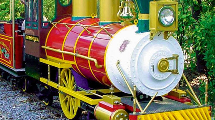 Colorful train ride at Hirakata Park, Japan, surrounded by lush greenery.