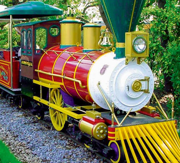 Colorful train ride at Hirakata Park, Japan, surrounded by lush greenery.
