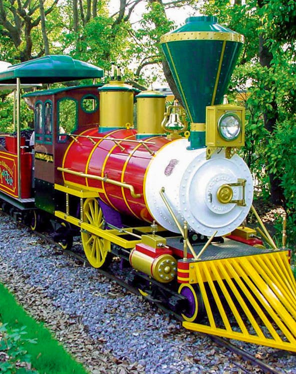 Colorful train ride at Hirakata Park, Japan, surrounded by lush greenery.