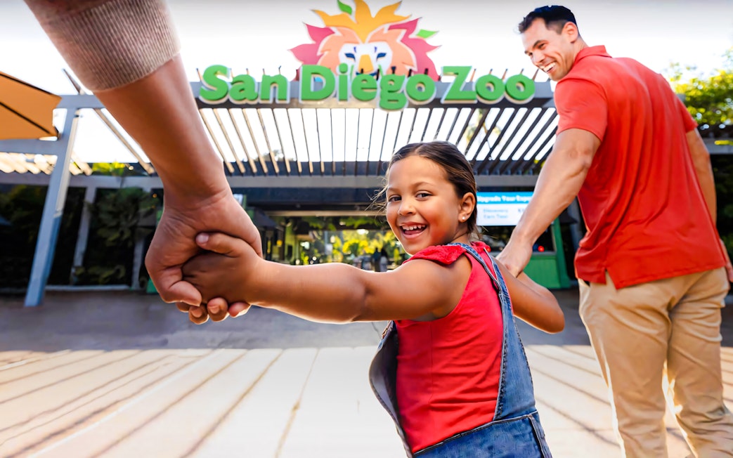 Family entering San Diego Zoo, child smiling and holding hands.