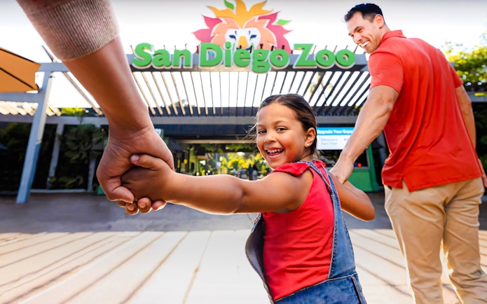 Family entering San Diego Zoo, child smiling and holding hands.