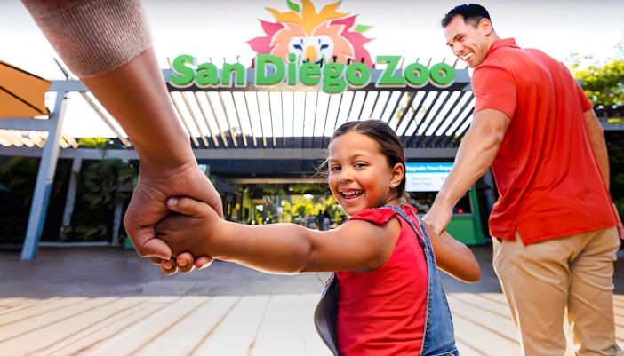 Family entering San Diego Zoo, child smiling and holding hands.