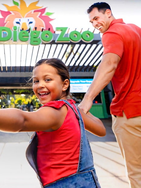 Family entering San Diego Zoo, child smiling and holding hands.