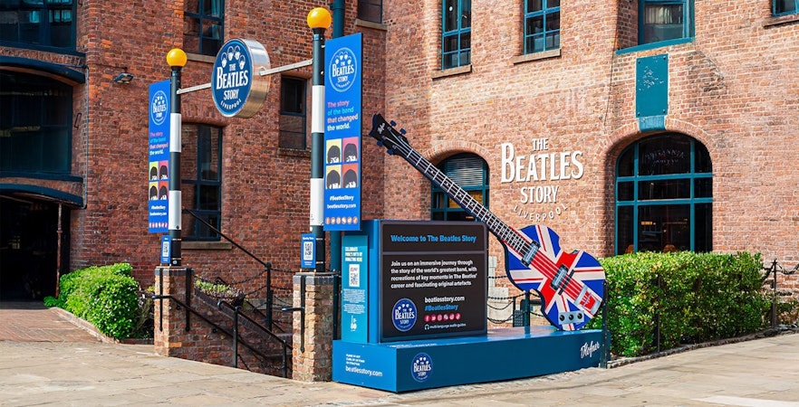 Exteriors of The Beatles Story museum in Liverpool with signage and guitar sculpture.
