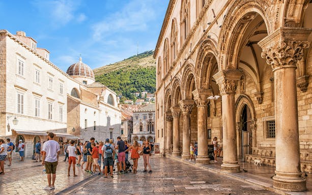 Group of tourists exploring Dubrovnik's Old Town near historic arches and buildings.