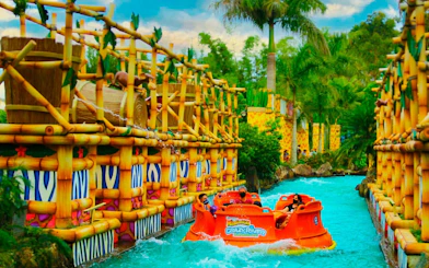 Raft on Crazy River ride at Beto Carrero World, surrounded by bamboo structures and lush greenery.